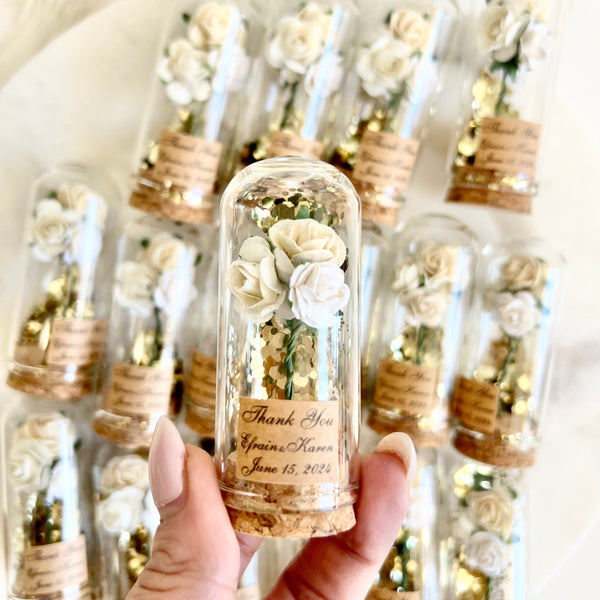 Bottle with preserved flowers and 'Thank You' message, surrounded by more bottles in the background.