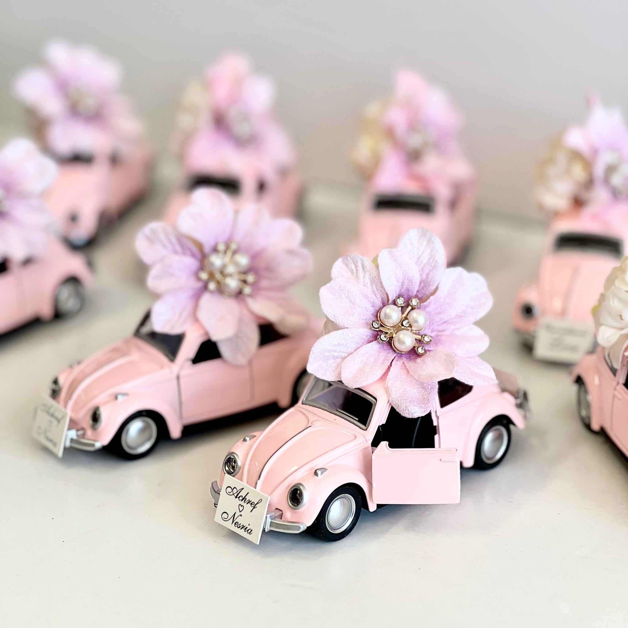 Small pink cars with floral decorations on a light gray background