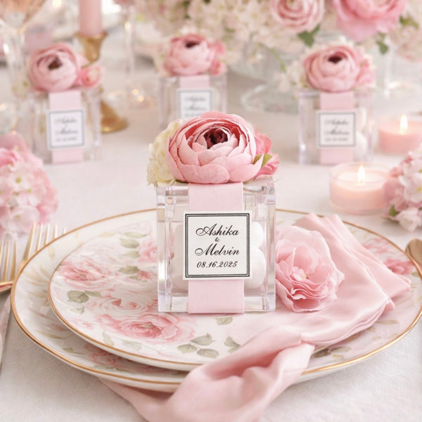 Elegant table setting with pink flowers, plates, and napkins on a white tablecloth.