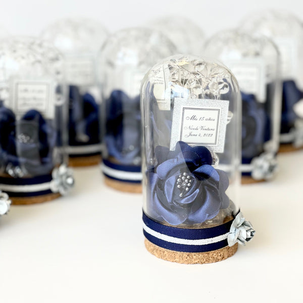 Decorative item in a glass dome with navy ribbon on a white surface