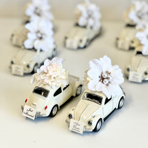 Decorative model cars with floral arrangements on a light background
