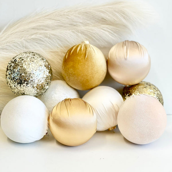 Decorative balls in gold, white, and silver on a white background