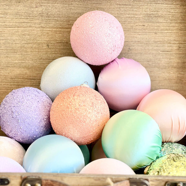 Pastel-colored bath bombs in a wooden suitcase on a textured surface