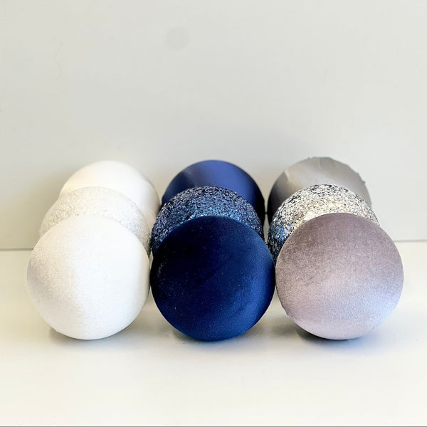 Four decorative eggs in white, blue, and gray on a light background