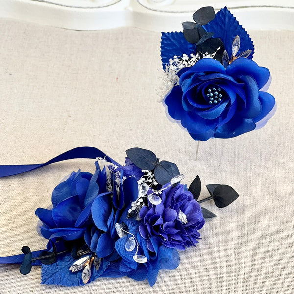 Two blue flower corsages on a beige surface