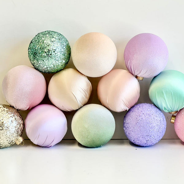 Decorative pastel and glittery ornaments arranged in a pyramid shape on a white background.
