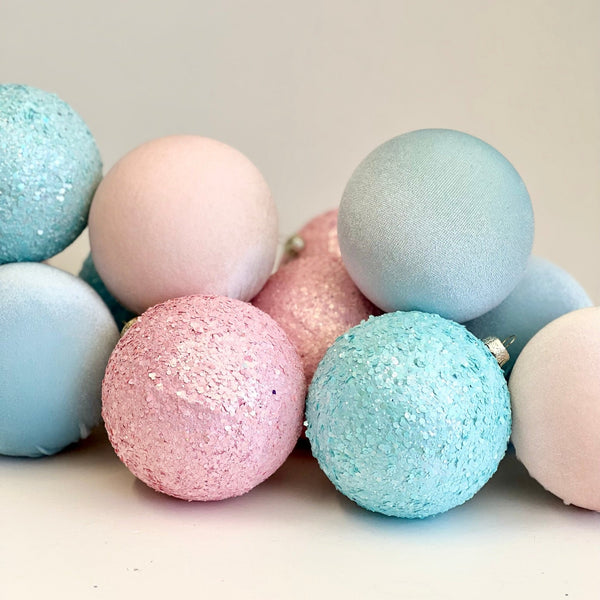 Pastel-colored bath bombs with glittery textures on a light background