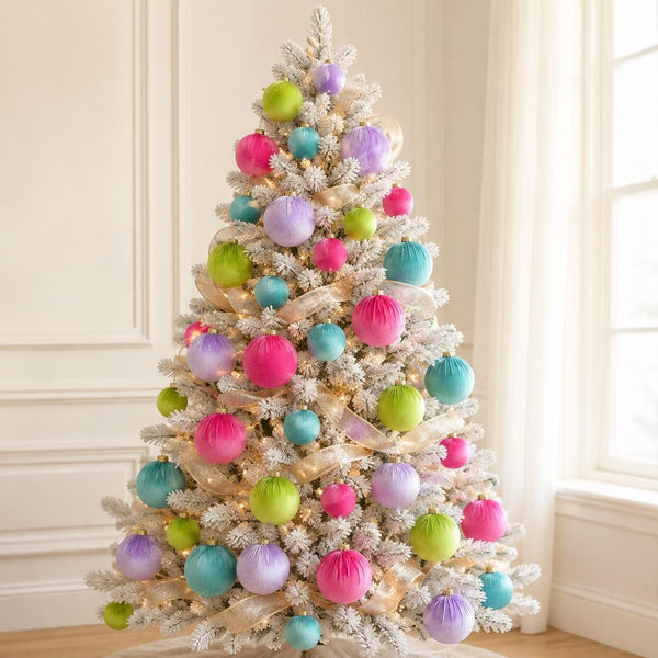 A flocked Christmas tree decorated with pastel pink, purple, teal, and lime green ornaments, hanging ribbons, and warm string lights in a bright room with cream walls and a window.